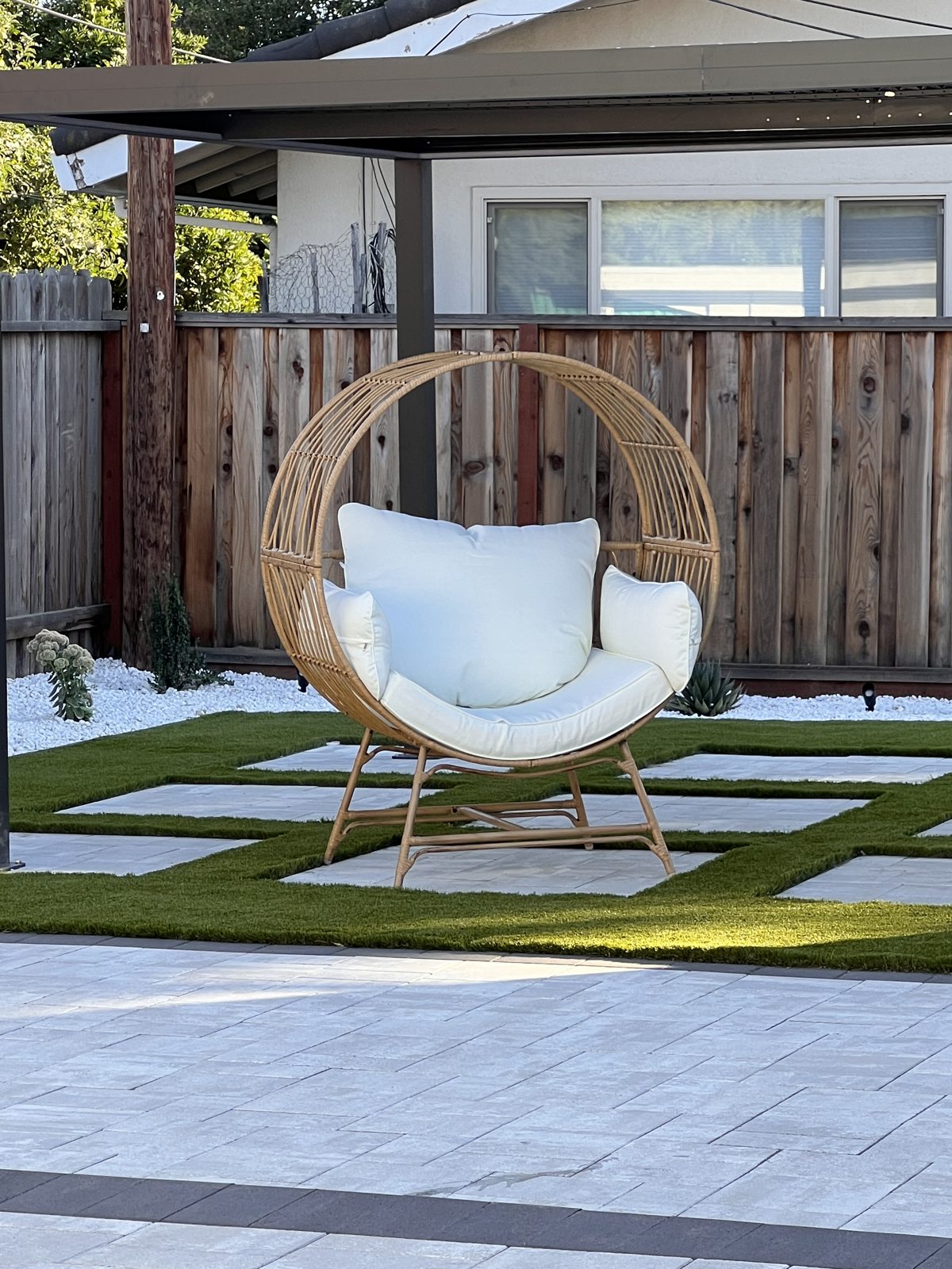 A suspended chair becomes a focal point within the patterned garden paving.