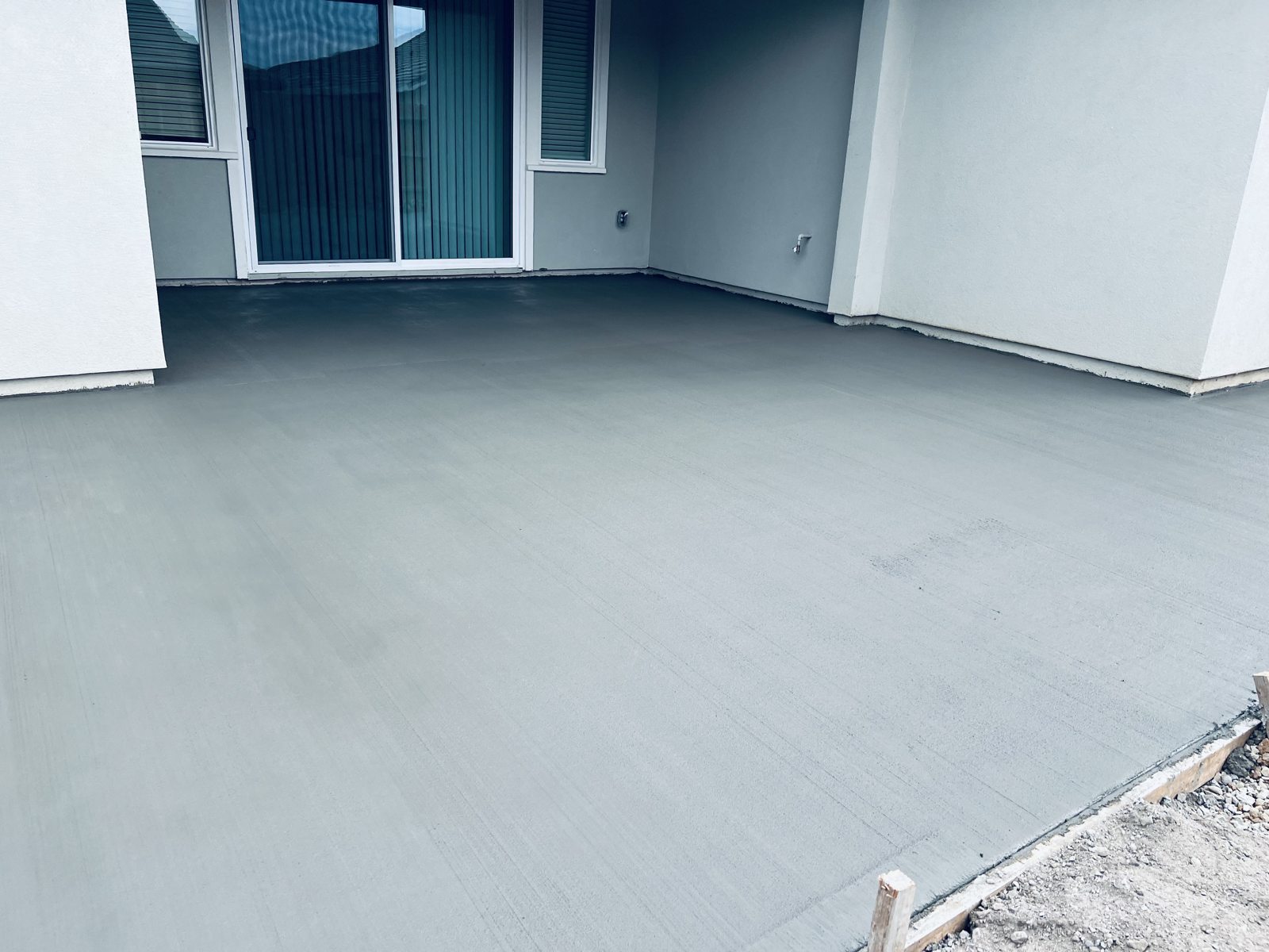 A clean concrete finish complements the covered corner of this backyard.