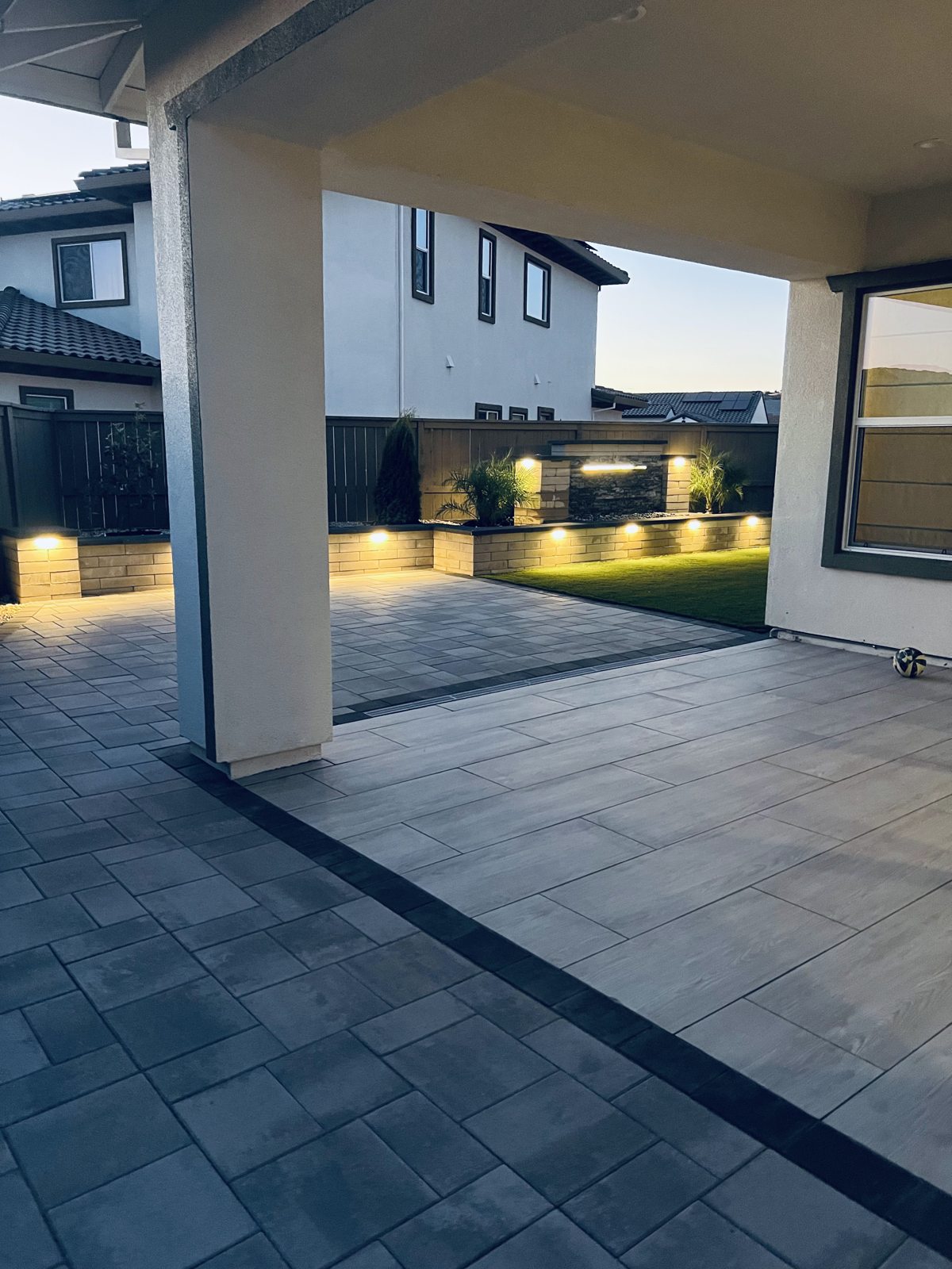 A covered patio frames the softly illuminated lawn and surrounding landscape.