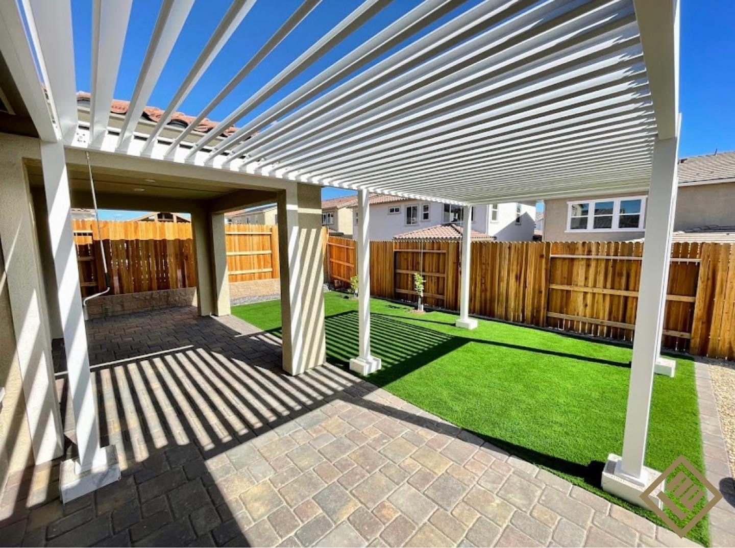 A shaded outdoor structure extends the living area beside the lawn.