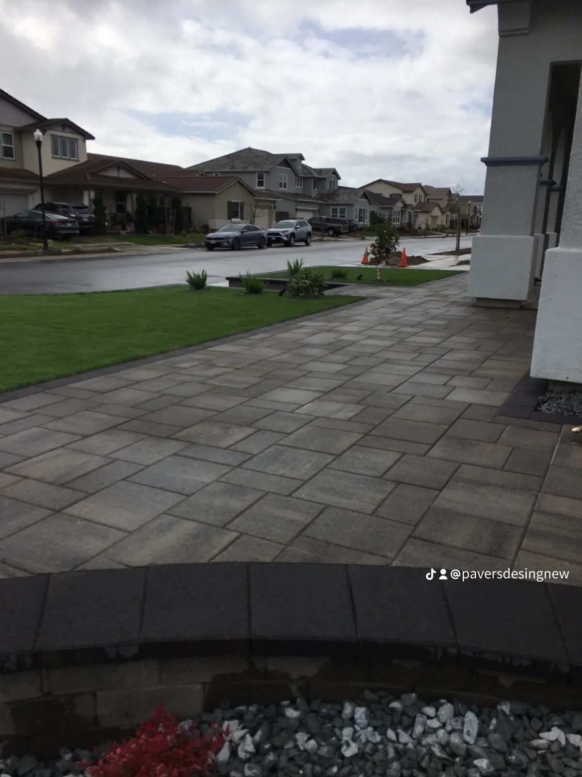 A broad paver surface connects the covered patio with the open garden.