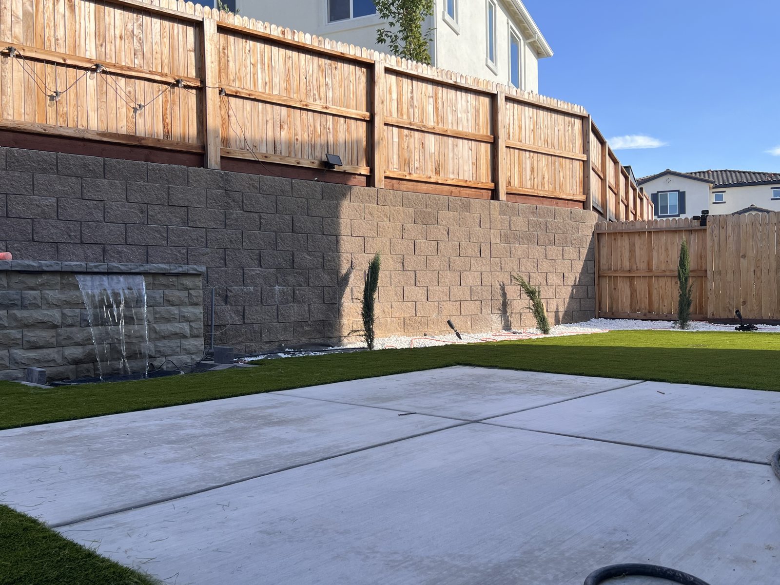 A long masonry wall and green lawn create a composed backyard boundary.