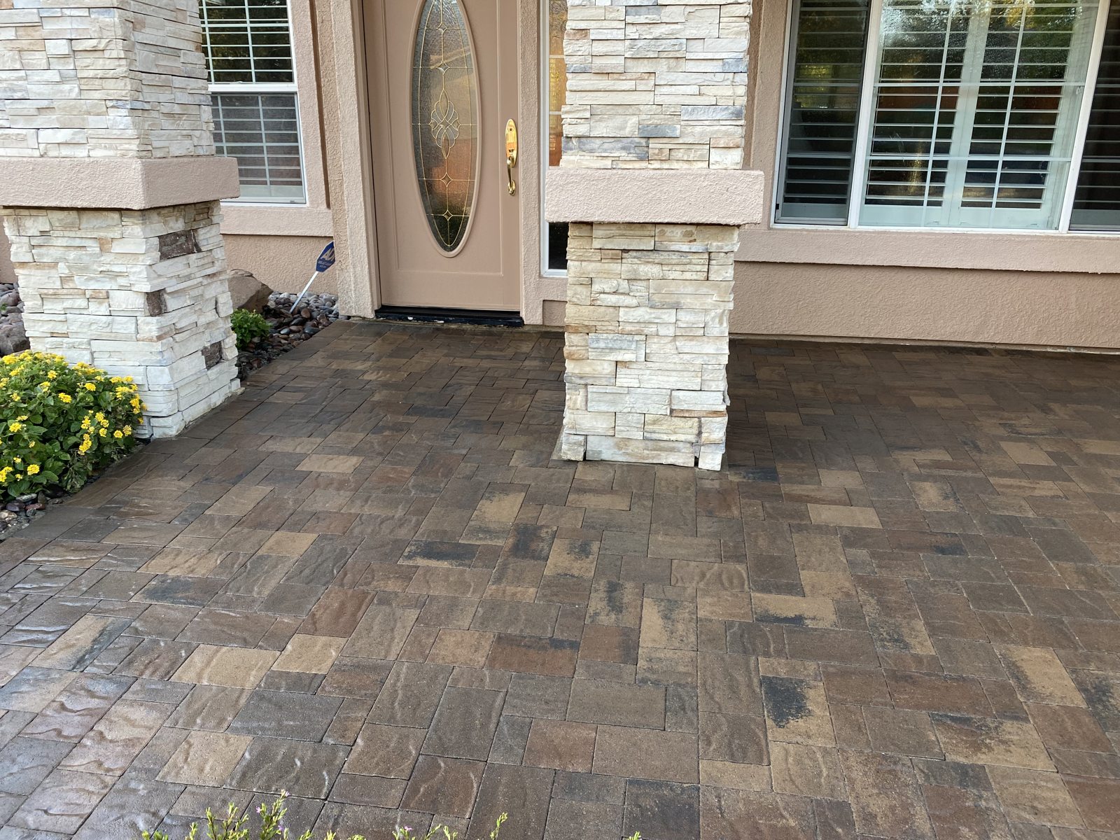 Mixed paver tones add warmth to the covered entrance and outdoor threshold.