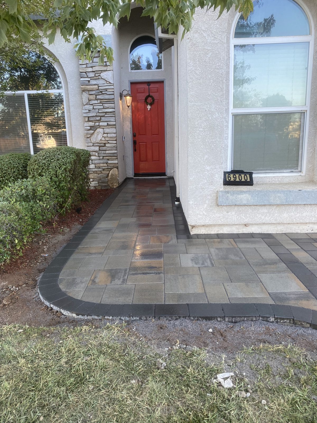 A curved paver entrance welcomes visitors with warm texture and a defined border.