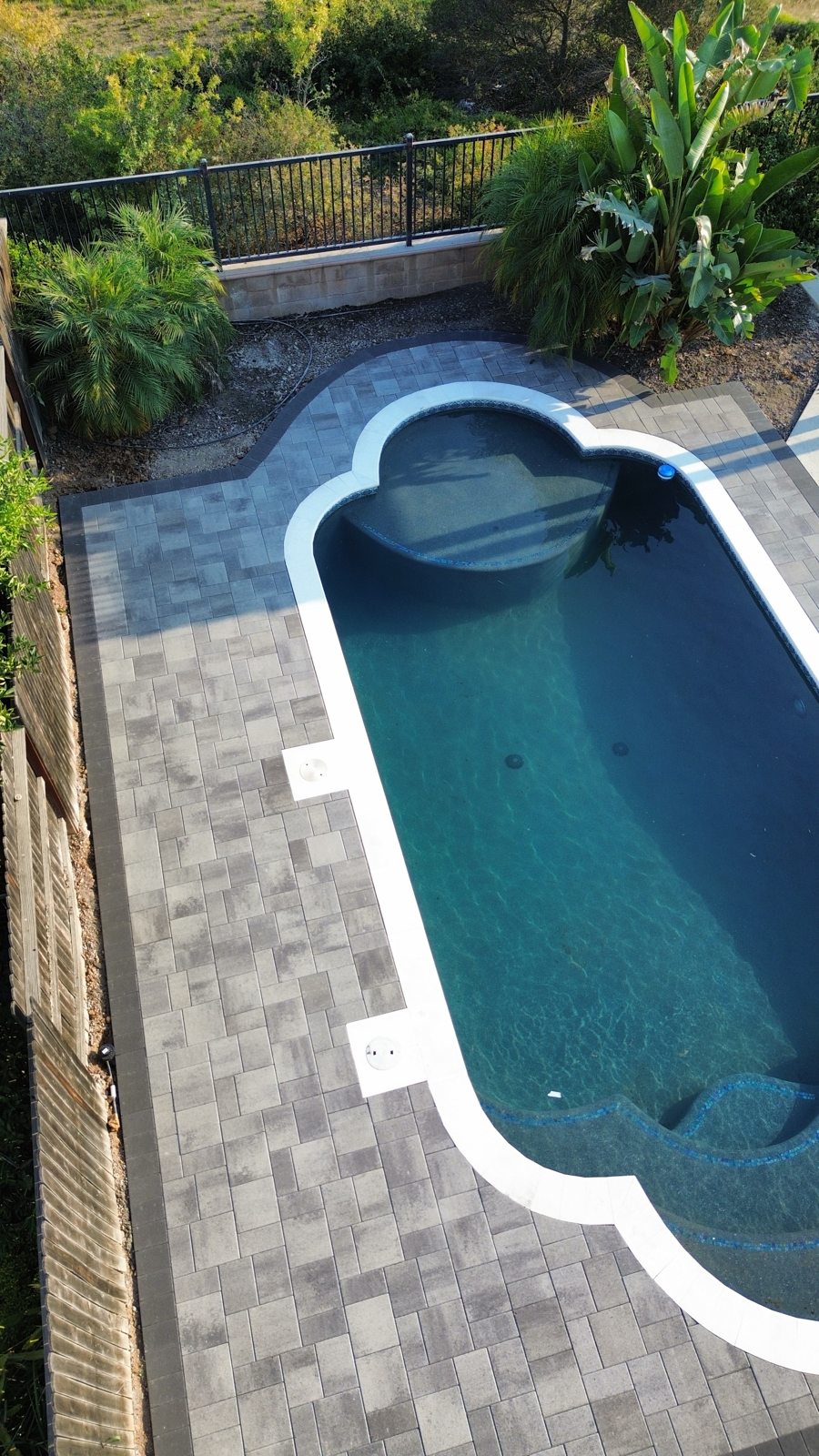 An overhead view reveals the pool’s curved form within its paved setting.