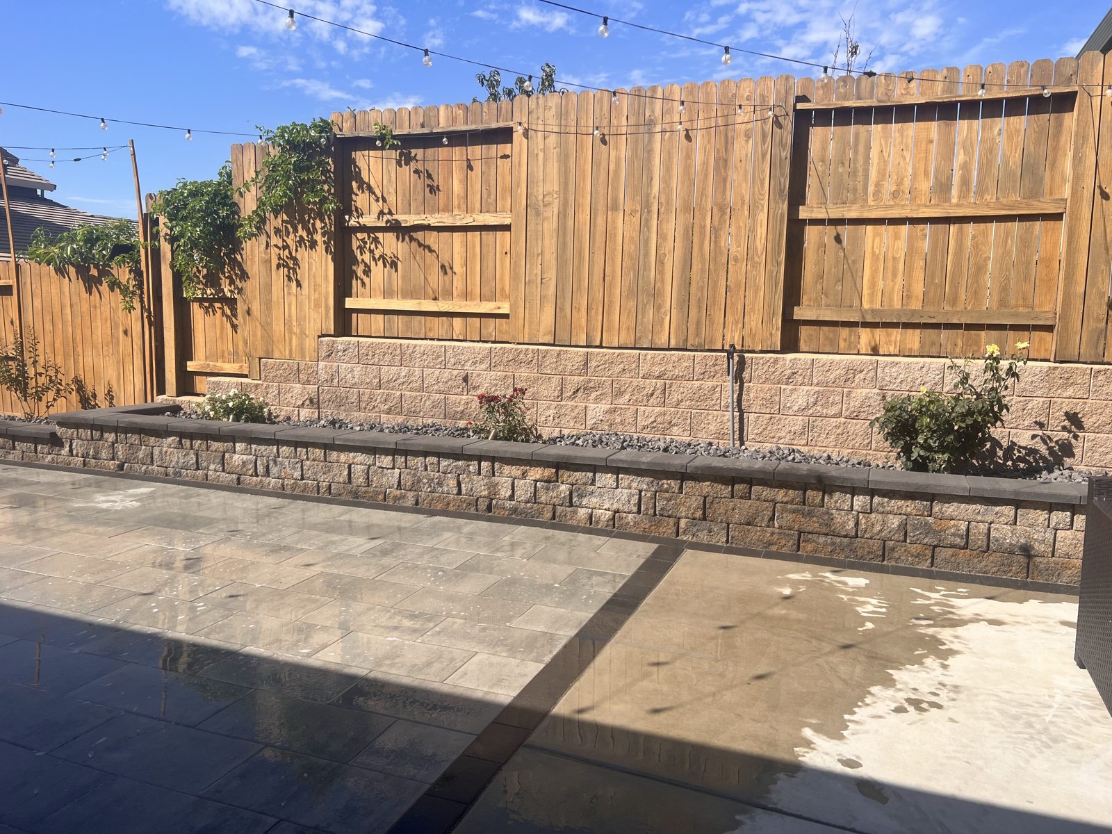 A planted retaining wall adds depth along the edge of the backyard patio.