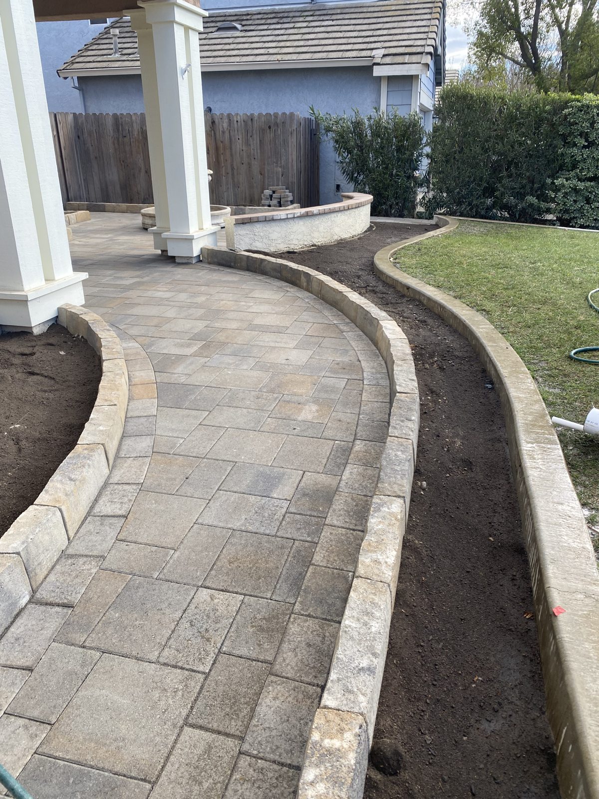 A curved paver walkway follows the home and softens the garden edge.