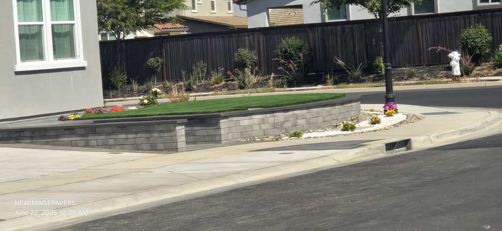 A long planted border and low wall organize the edge of the front lawn.