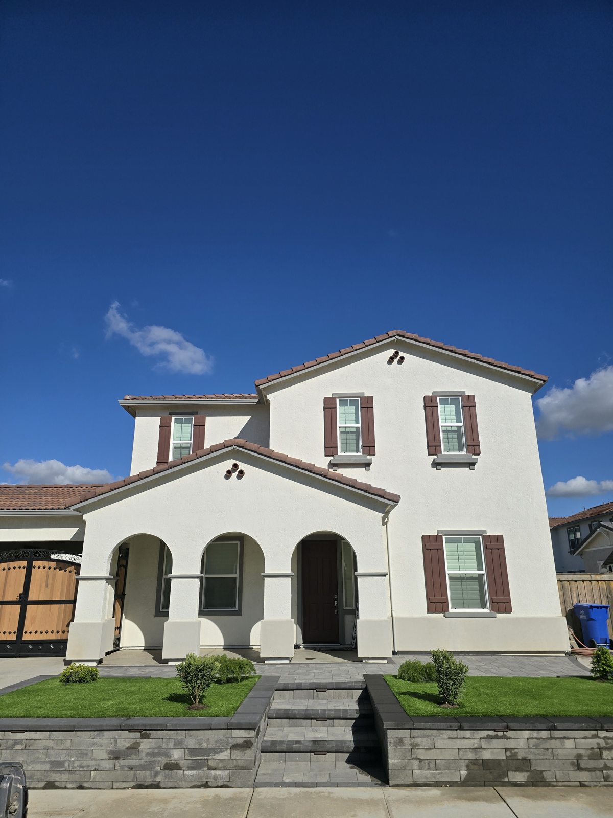 A raised lawn and sculpted front boundary complement the home’s facade.