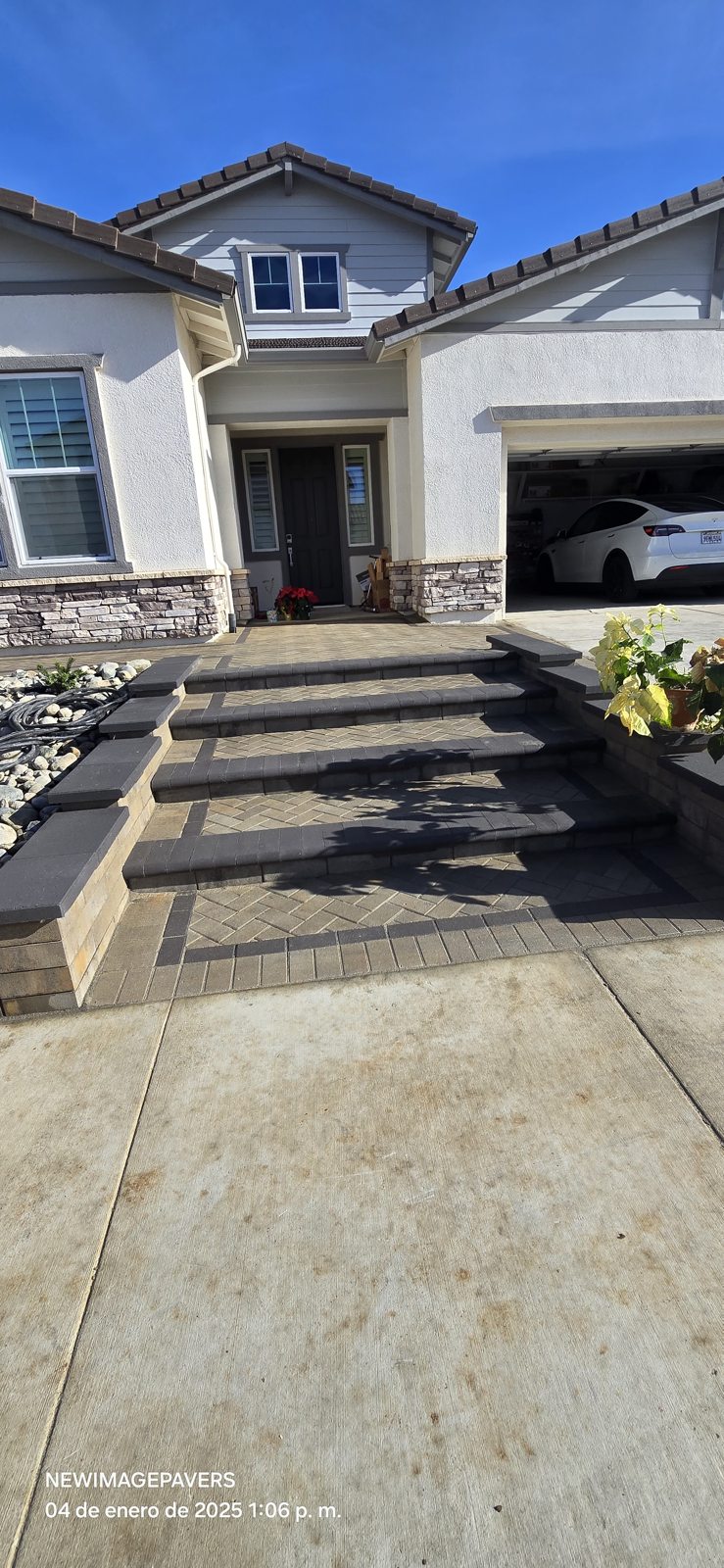 Crisp steps and gray pavers create a refined approach to the home.