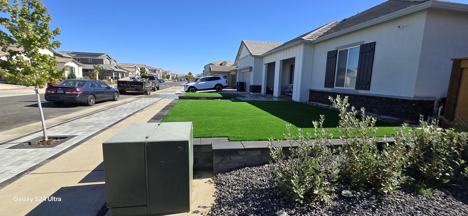 A raised green lawn contrasts with the geometric lines of the front-yard hardscape.