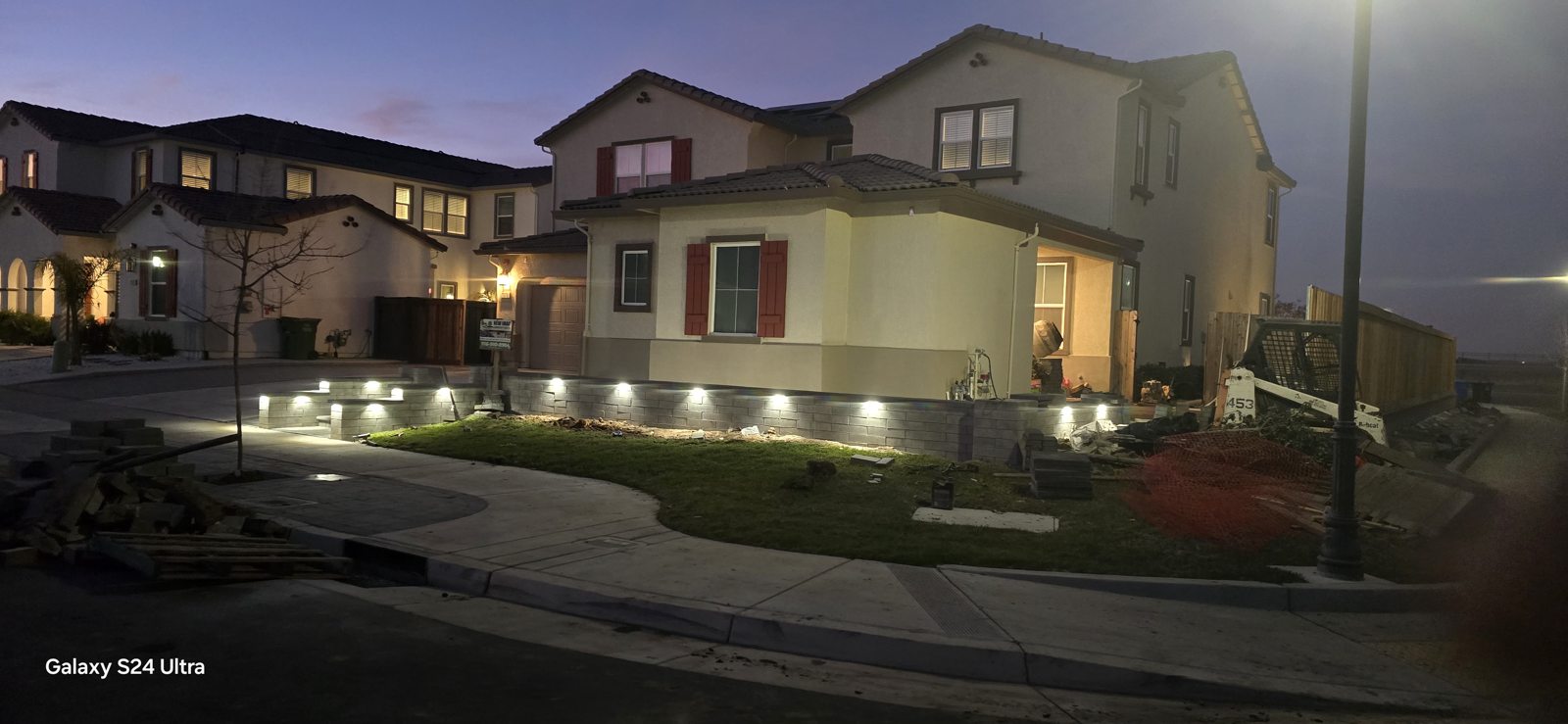 A nighttime view reveals the layered lighting across the front of the property.