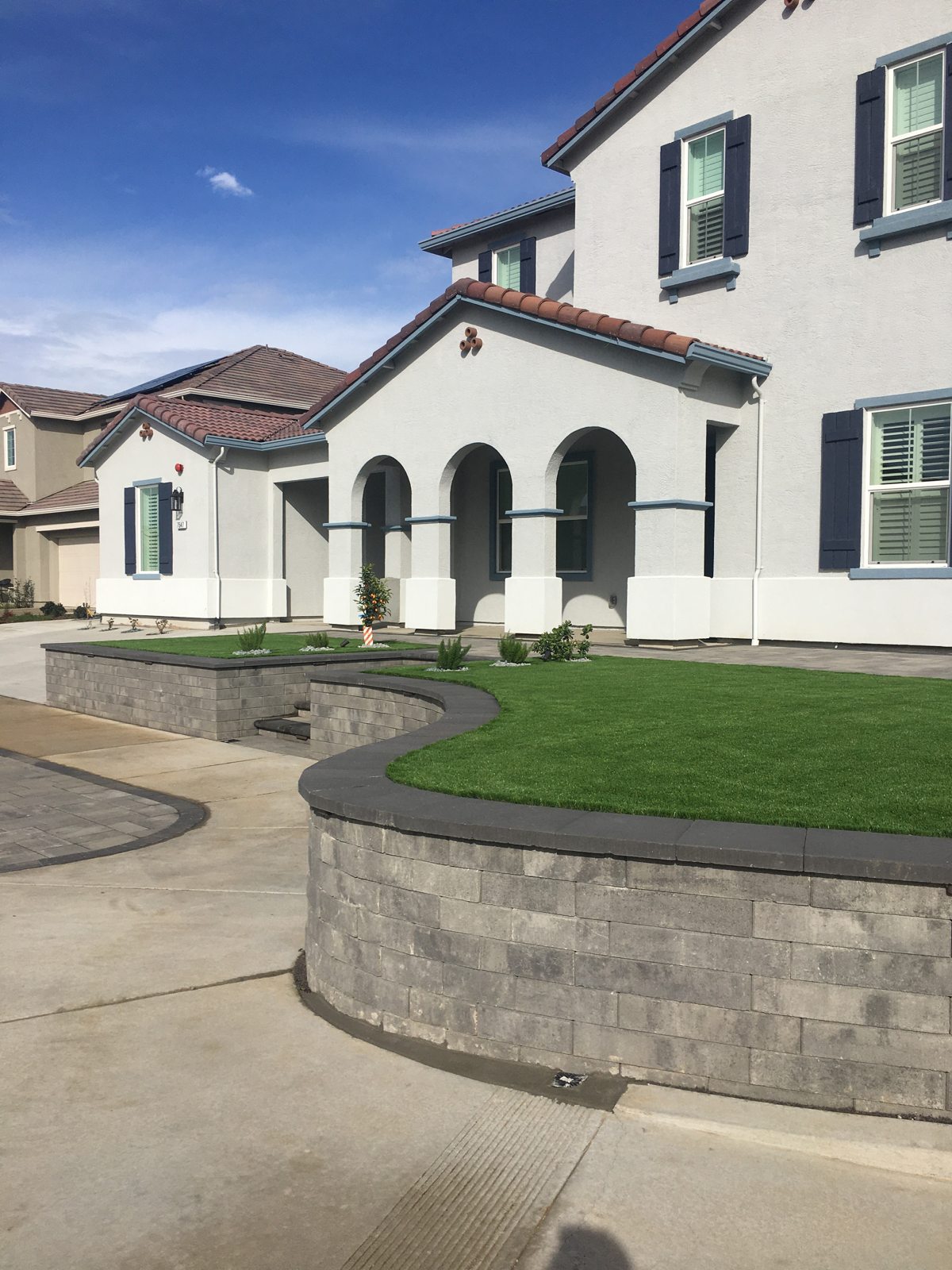 A curved low wall follows the green lawn and complements the home’s facade.
