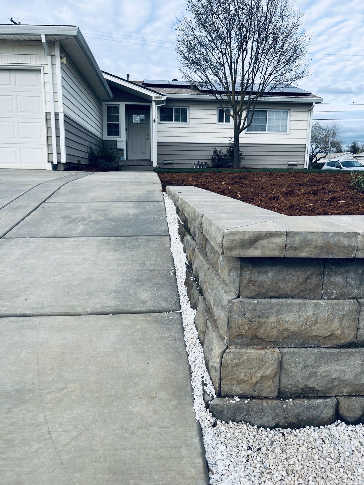 A low retaining wall provides a defined edge beside the driveway.