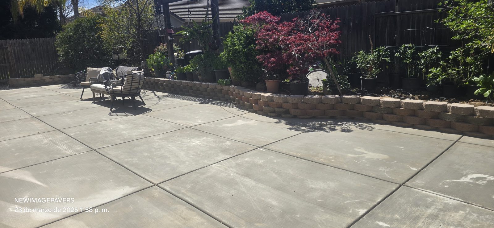 A low stone border separates the paved terrace from established planting.