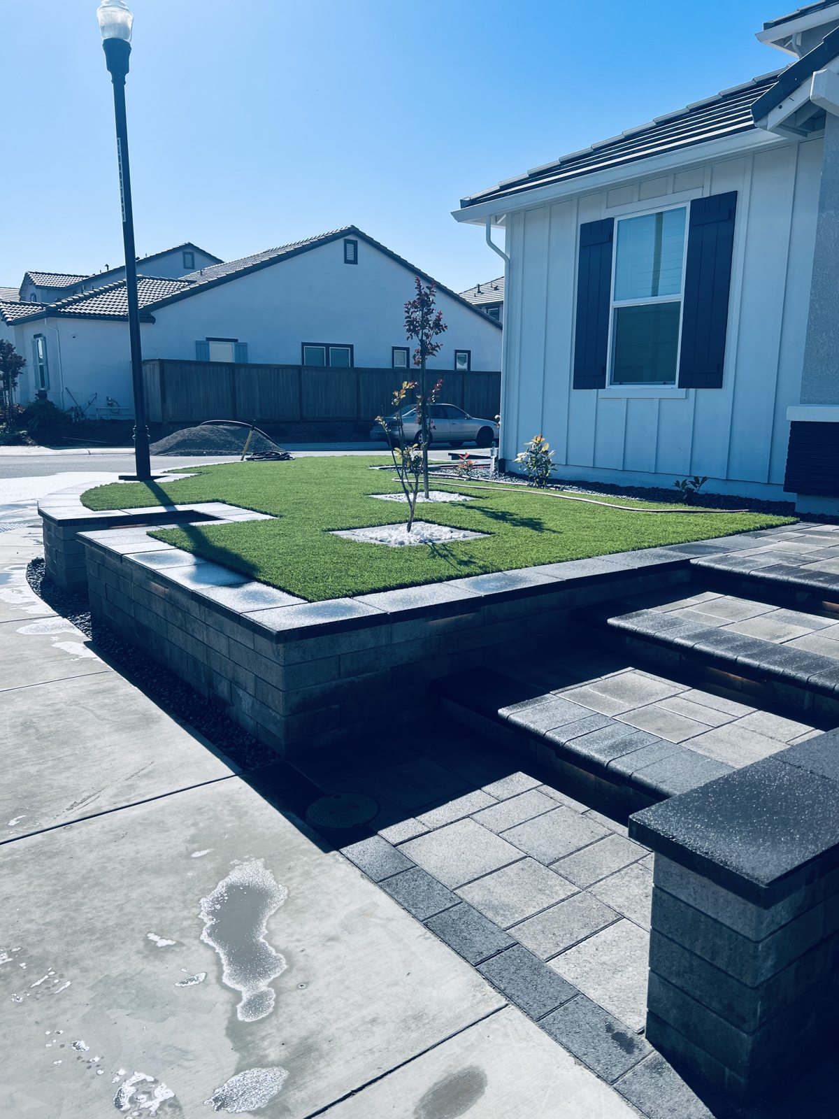 A raised green area is framed by crisp masonry edges and paved access.