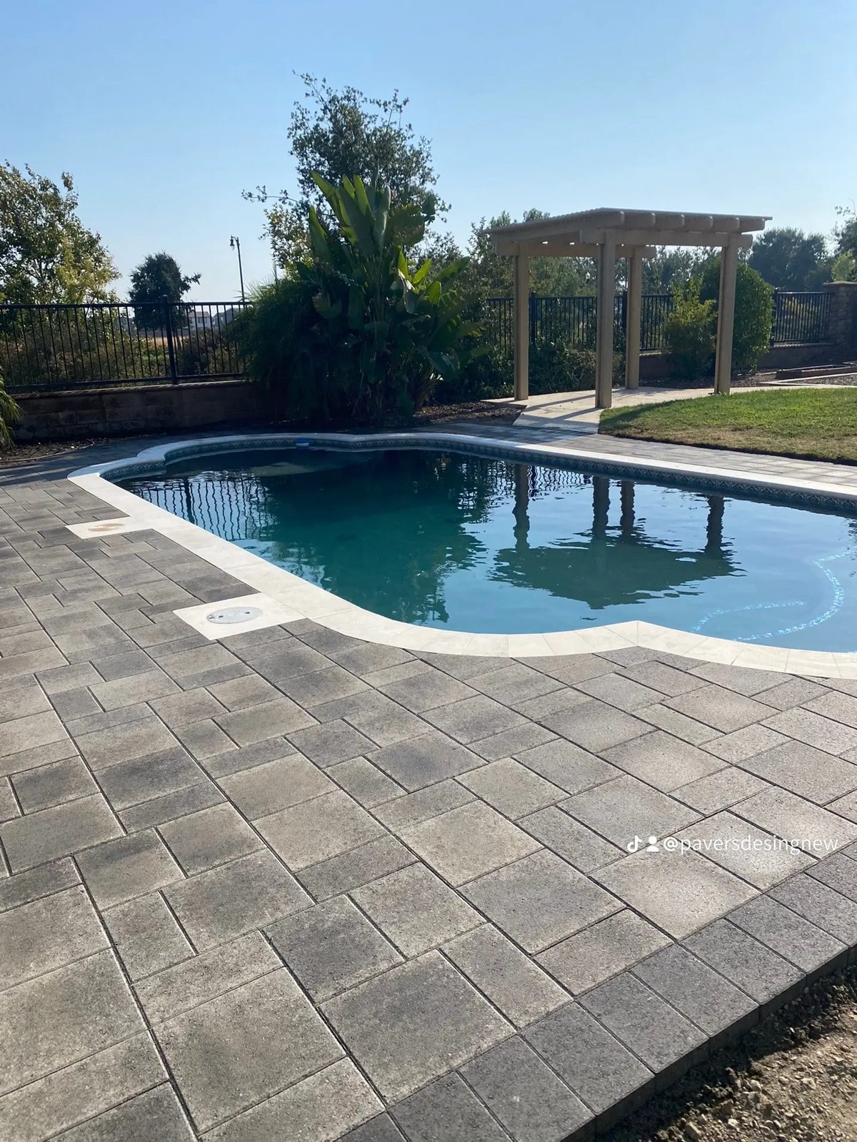 Gray pavers follow the pool edge and connect the water with the surrounding garden.