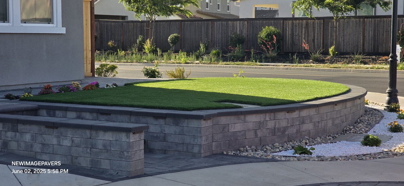 A curved retaining wall gives the green front garden a polished edge.