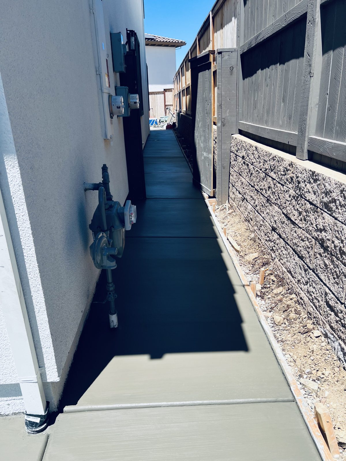 A narrow concrete walkway makes efficient use of the space beside the house.