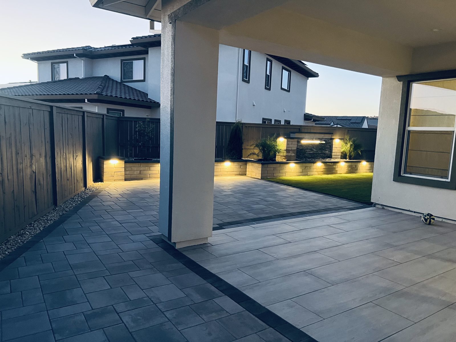 The covered patio opens onto a softly illuminated backyard composition.