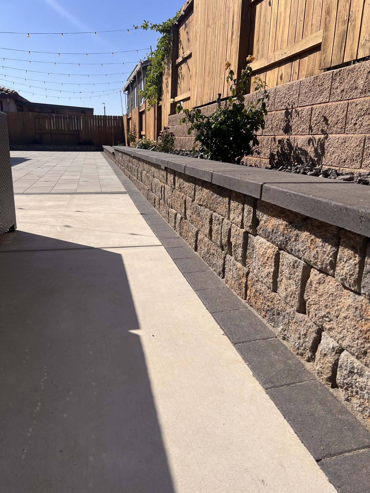 The wall cap and textured block face create a strong, continuous patio boundary.