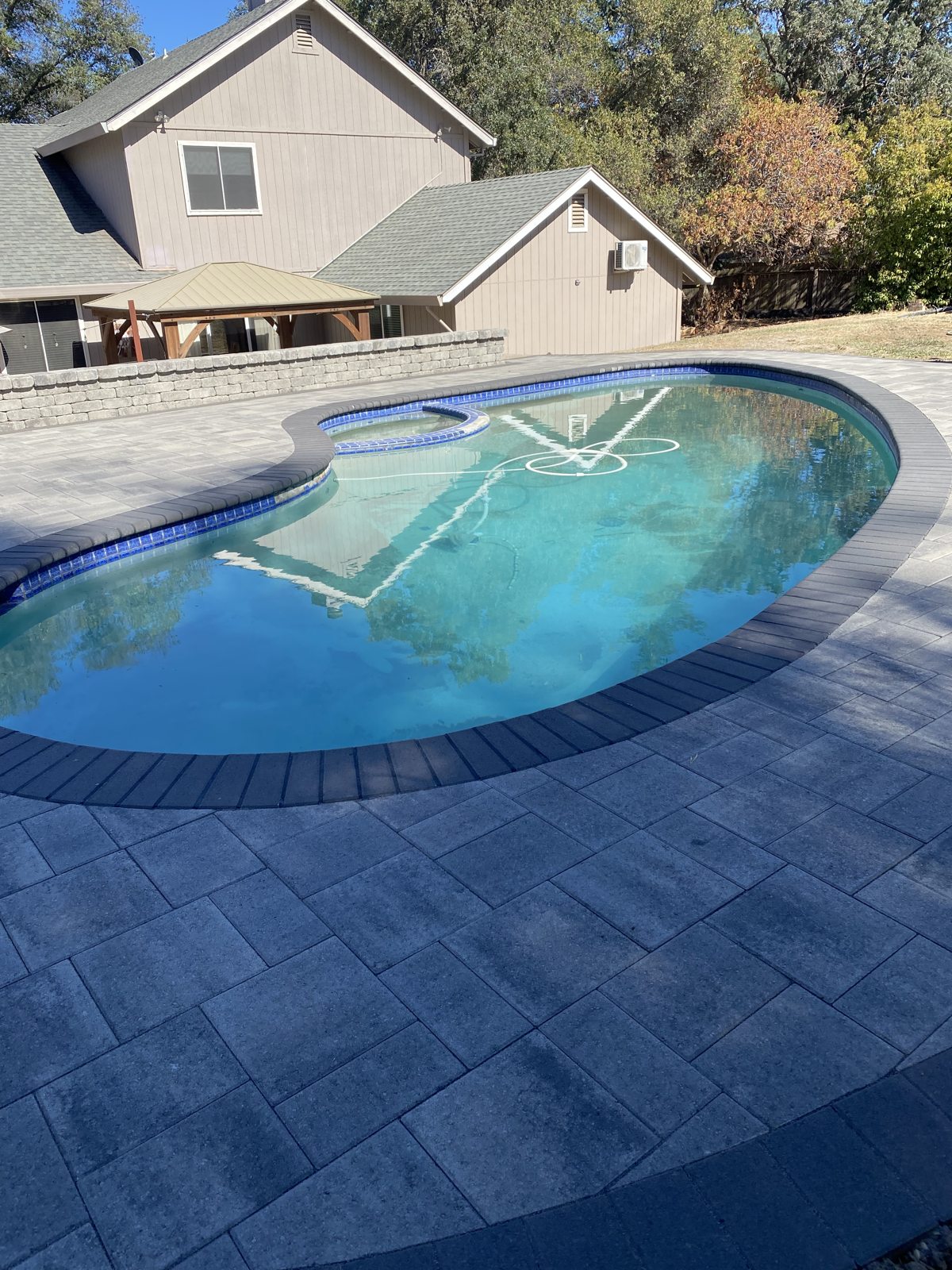 A rounded pool and broad paver surround create a welcoming space for outdoor leisure.