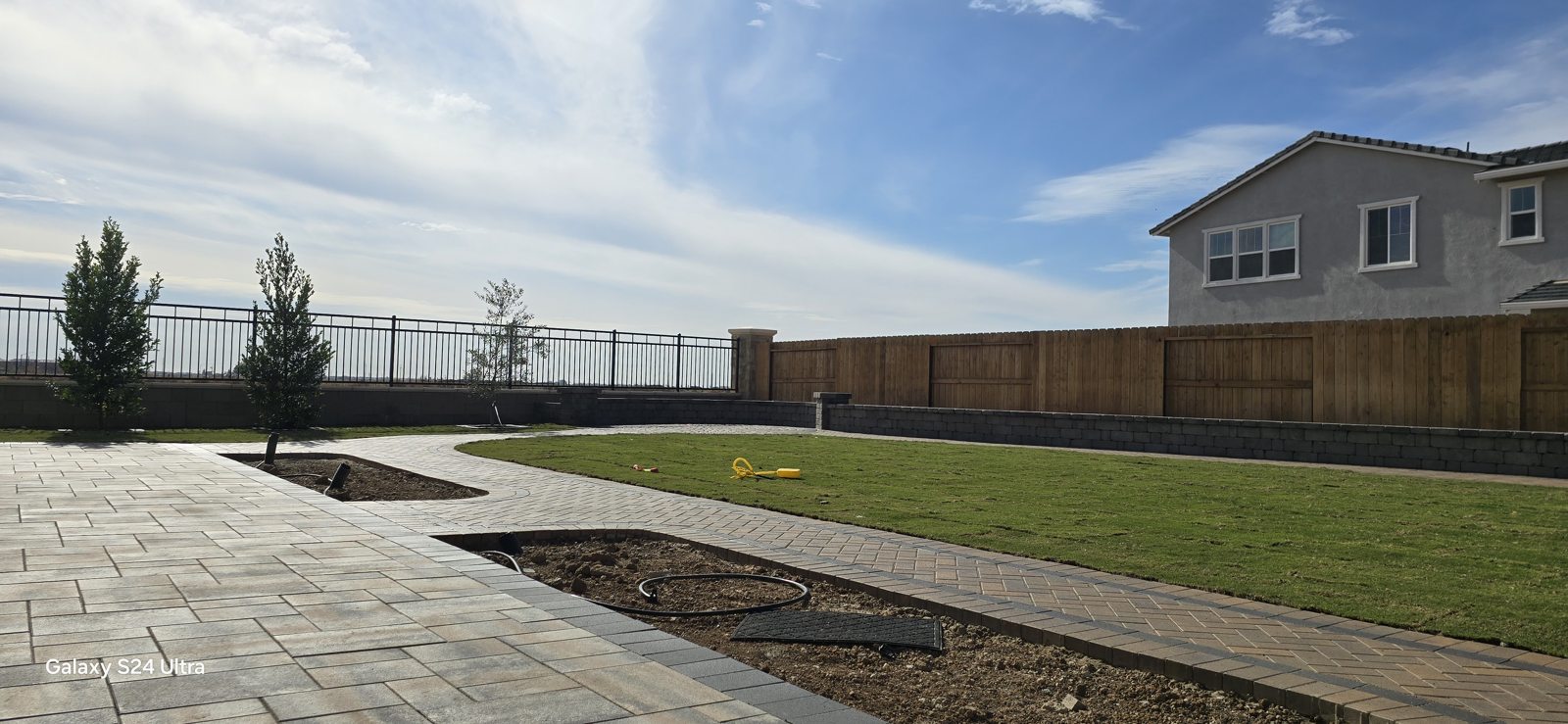 A sweeping paved area meets an open lawn for a spacious backyard composition.
