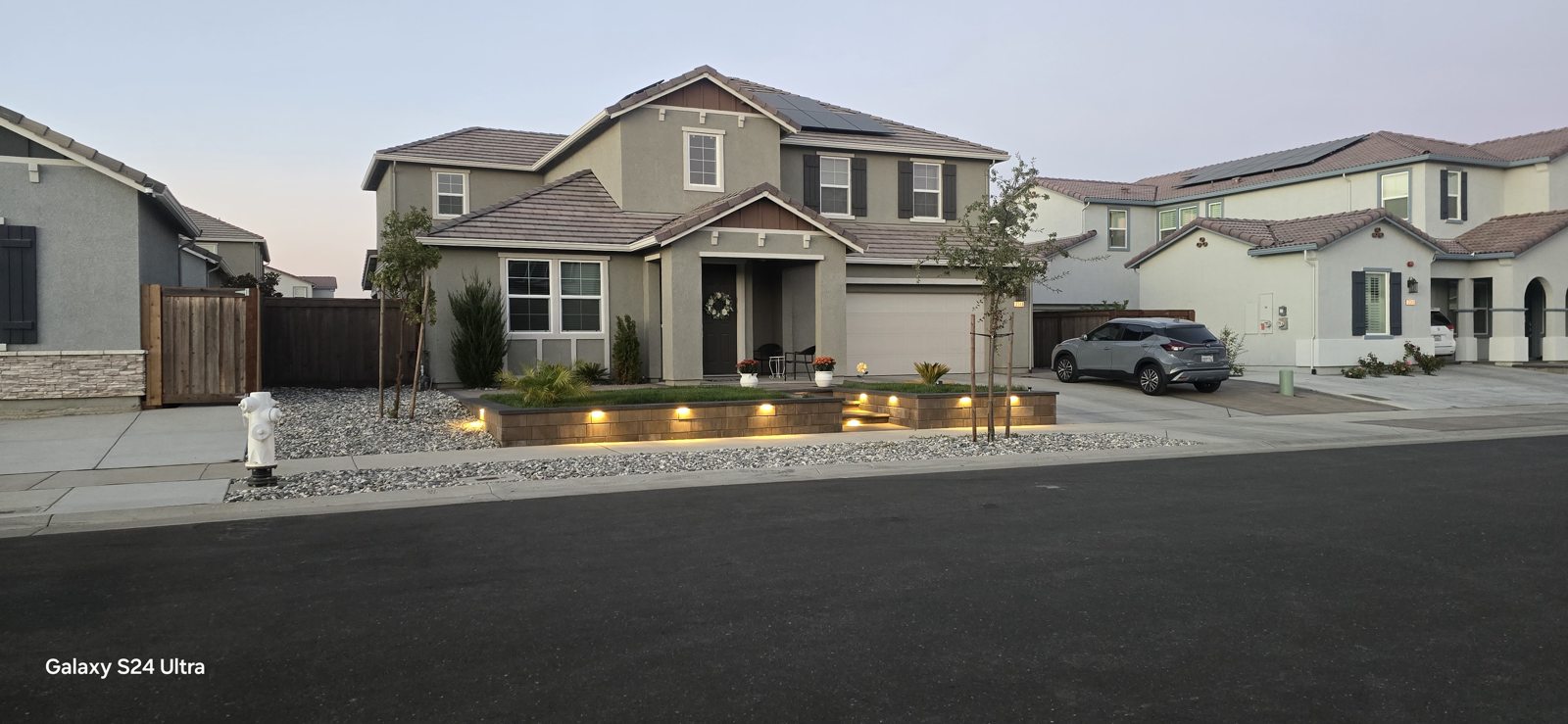 Warm lighting gives the front garden and low walls a welcoming evening presence.