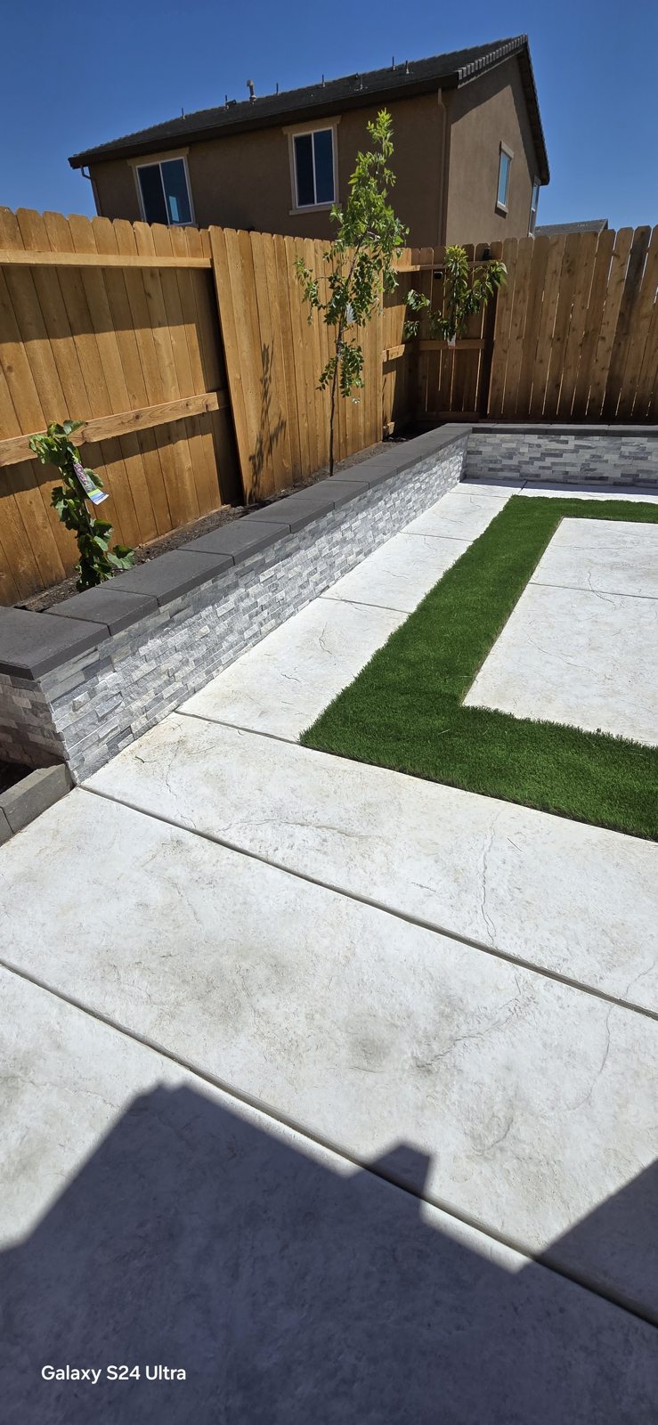 A long retaining wall defines the boundary beside the narrow paved passage.