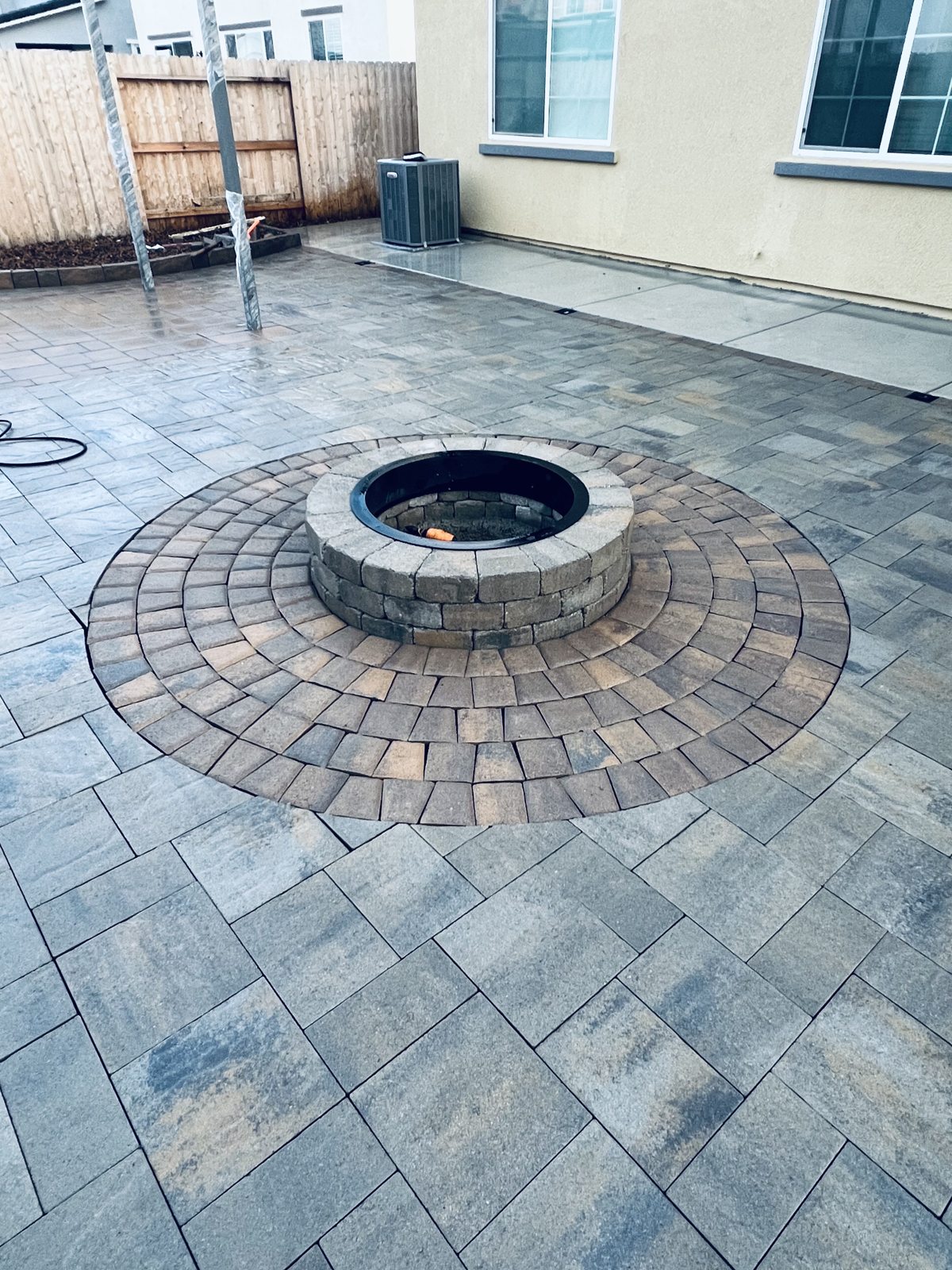 A circular paver detail emphasizes the fire pit at the heart of the patio.