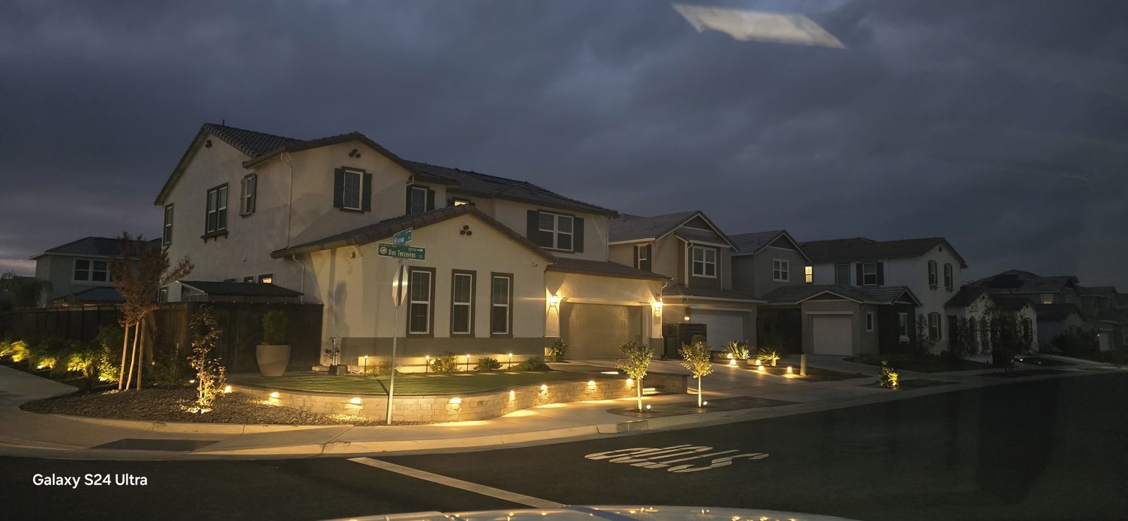 An illuminated corner landscape brings definition to the home after sunset.
