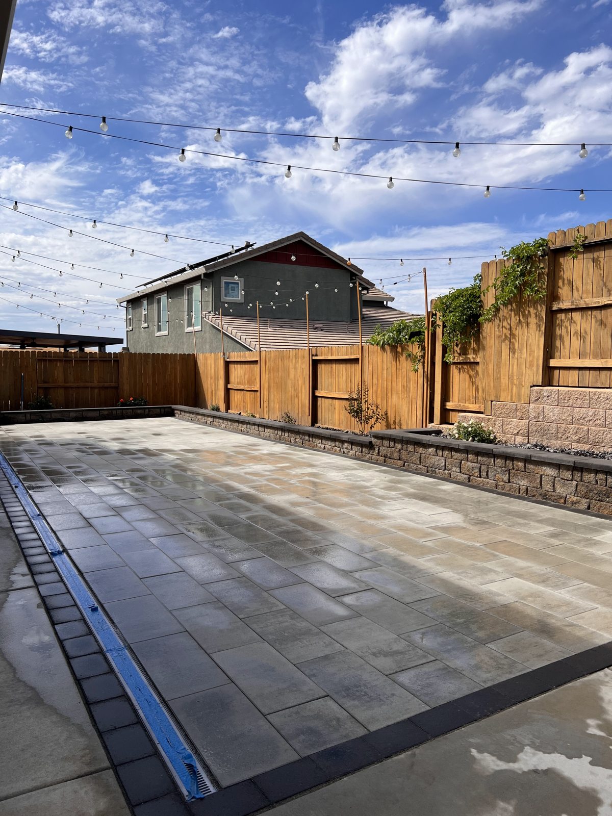 An expansive paver patio brings clean geometry to a fenced backyard.