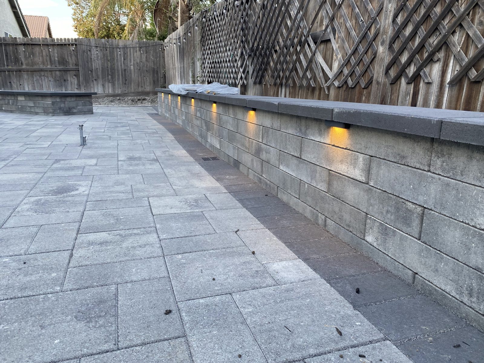 Small wall lights add a gentle glow along the paver terrace.