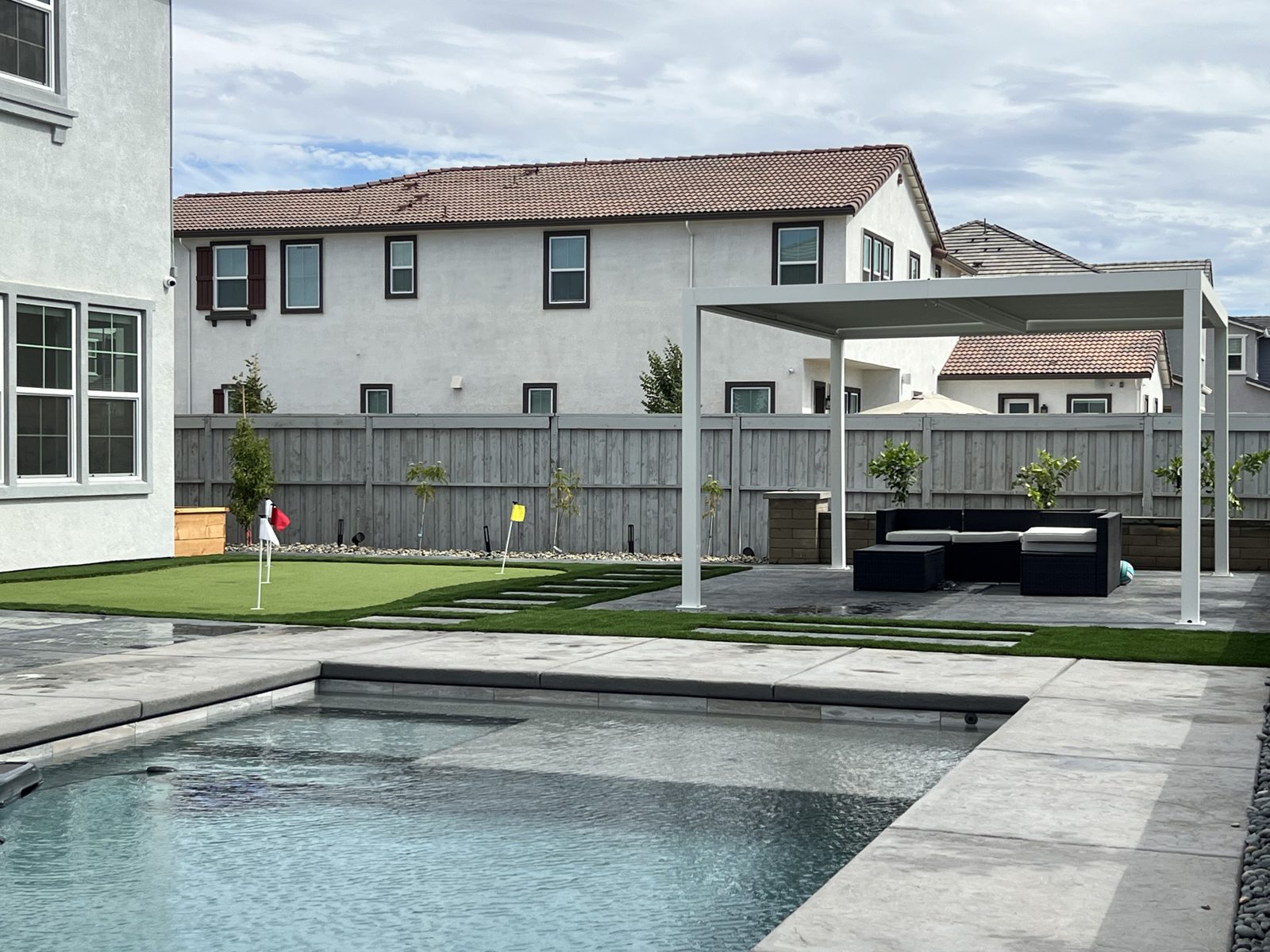 A rectangular pool and spacious surrounding paving create an open backyard setting.