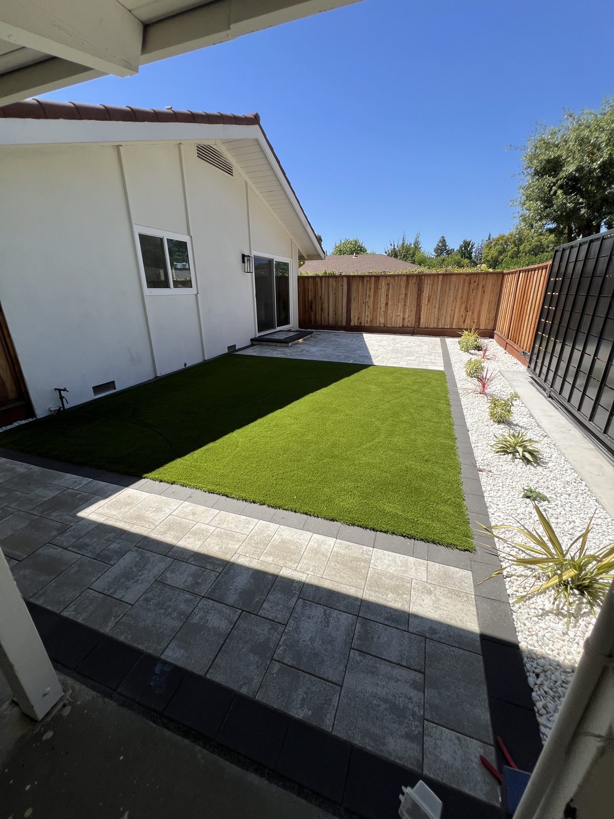 A compact lawn, paver path and retaining wall create a balanced side-yard layout.