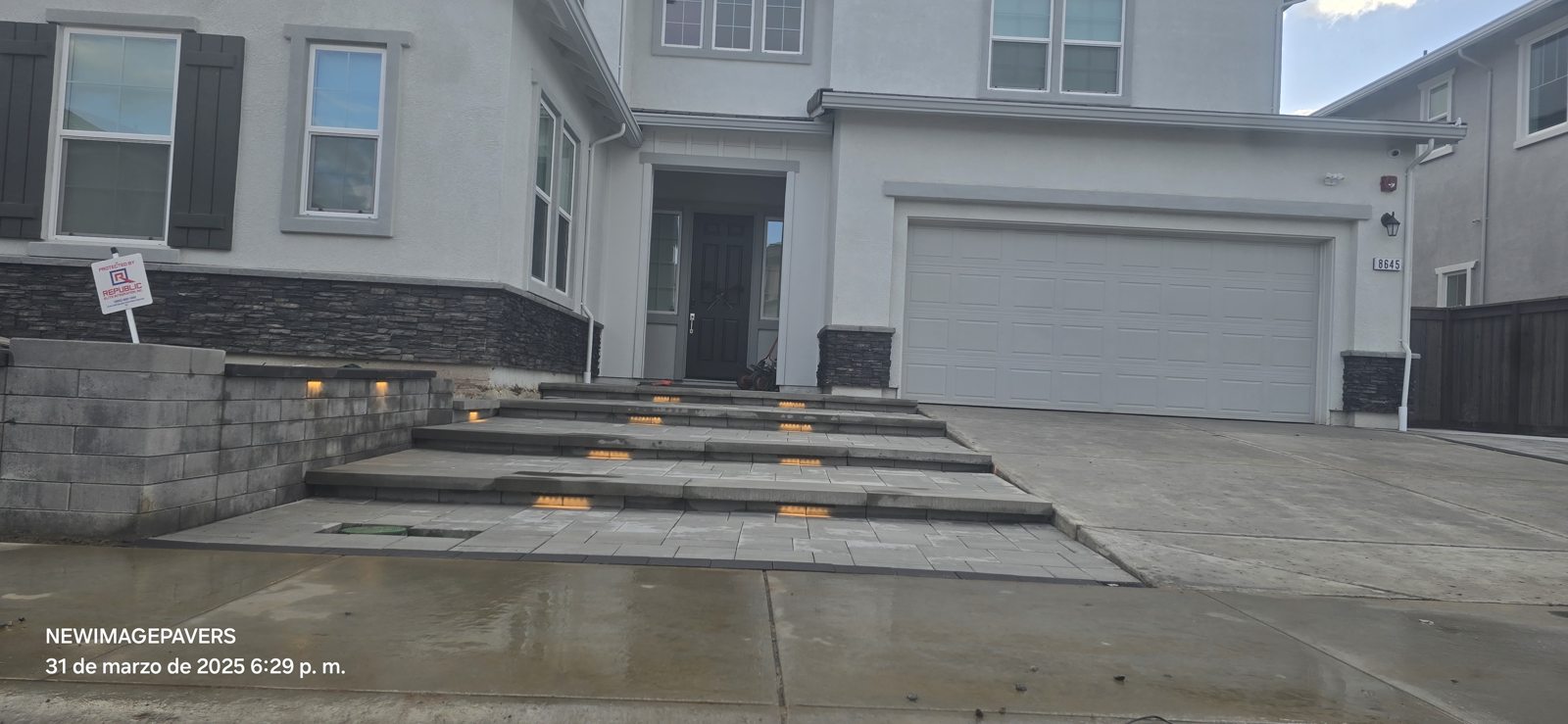 Integrated lighting draws attention to the broad front steps and textured walls.