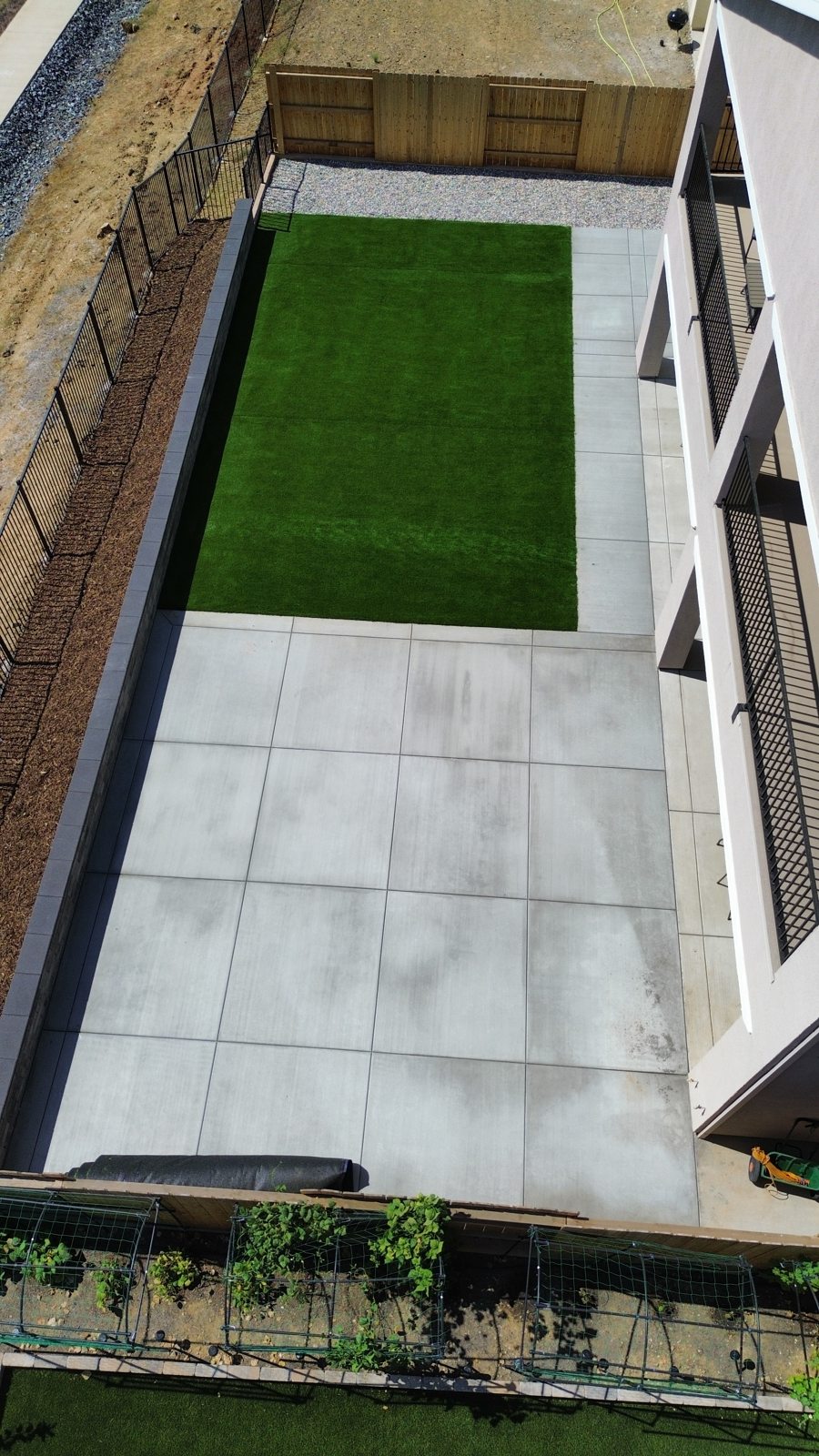 An overhead view highlights the contrast between the green lawn and pale paving.