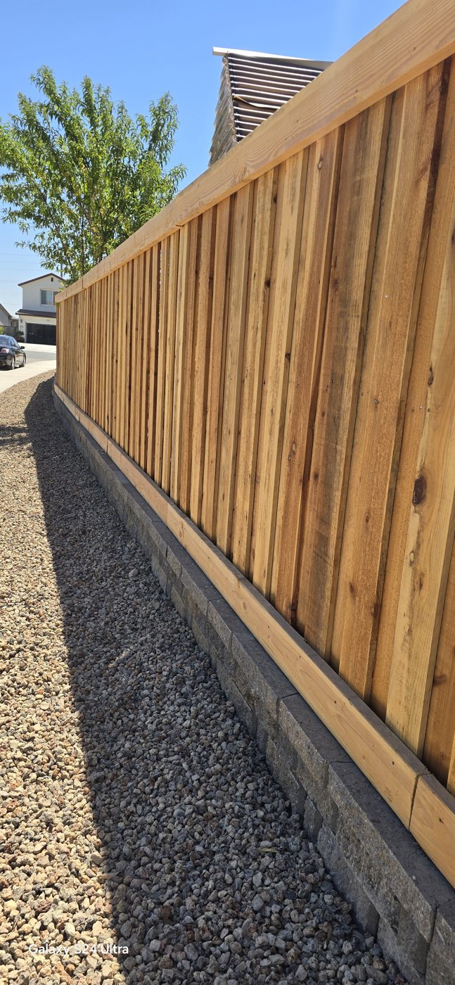 Natural wood boards create a warm privacy boundary above the textured stone base.