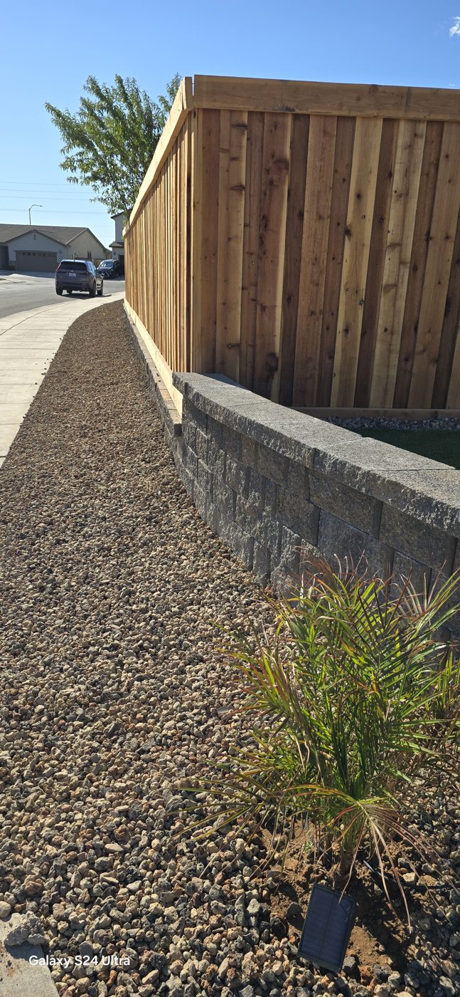 A neatly finished fence corner meets a planted gravel border.