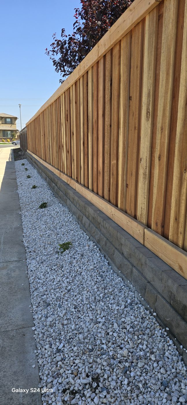 Vertical wood boards and decorative stone define a tidy property boundary.