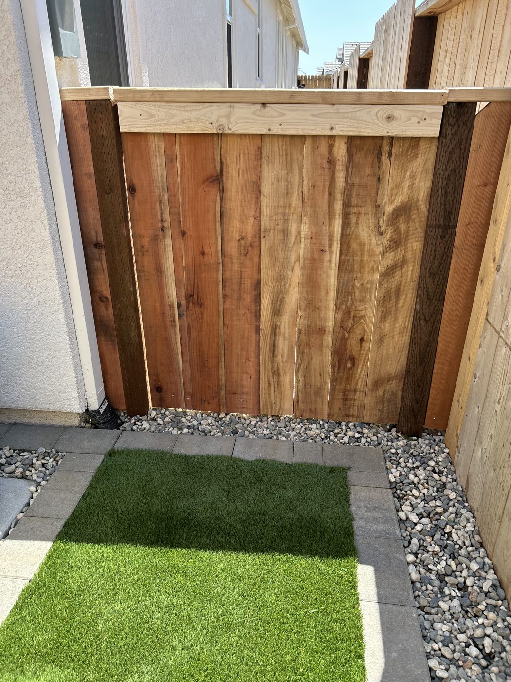 A timber gate closes the end of a compact green side yard.