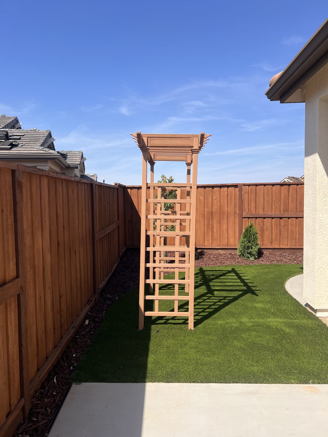 Wood fencing encloses a private green play area beside the home.