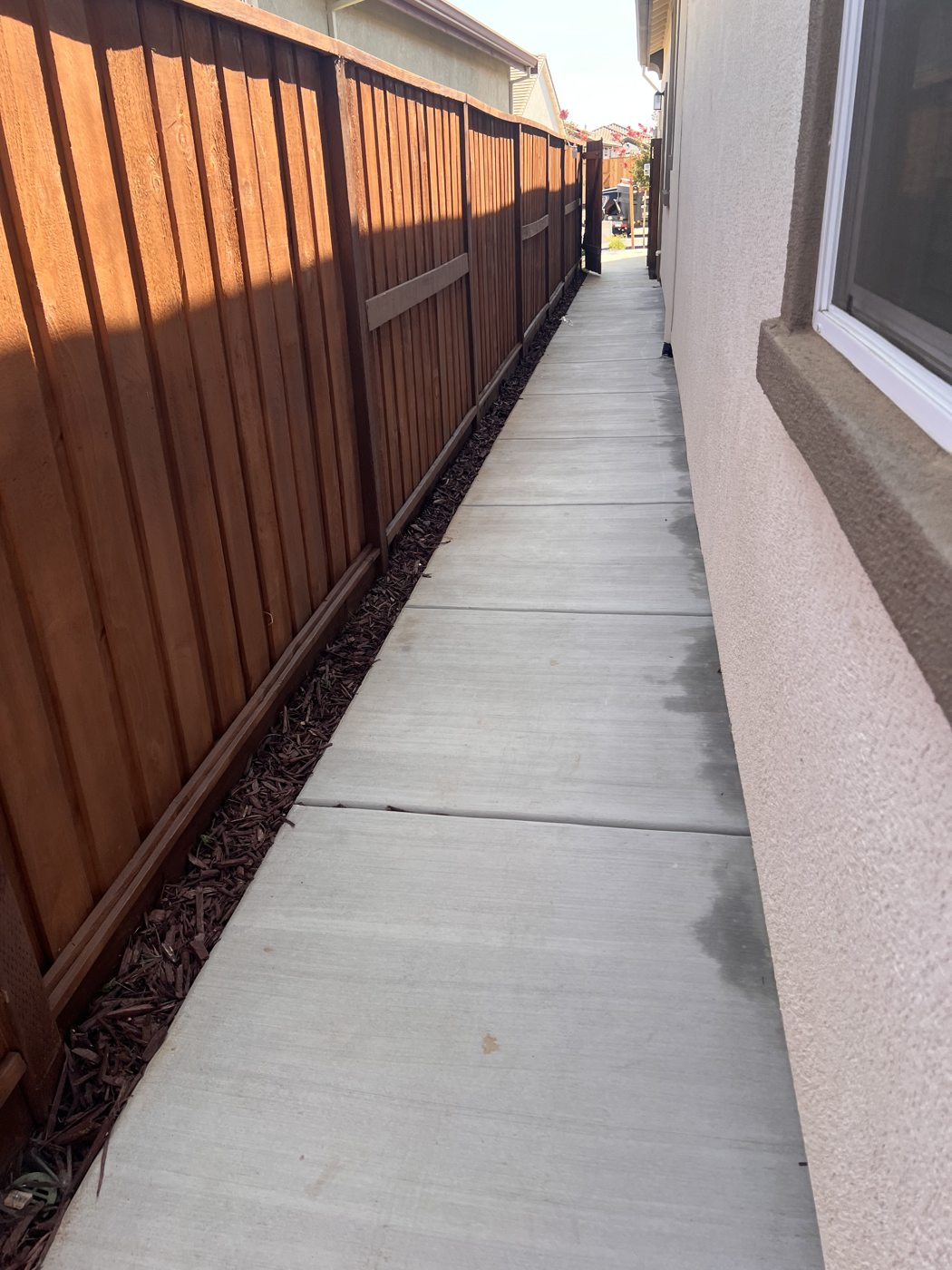 A warm-toned fence gives definition to the narrow concrete side passage.