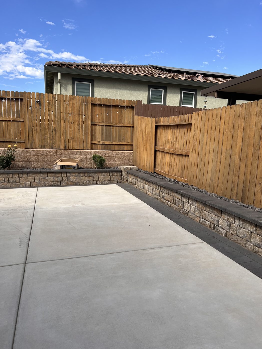 Wood fencing and a raised border frame the open concrete patio.