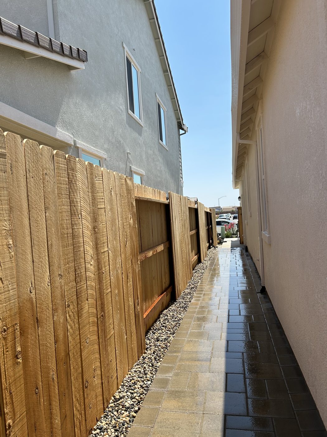 A tall wood fence creates a defined boundary along the narrow side passage.