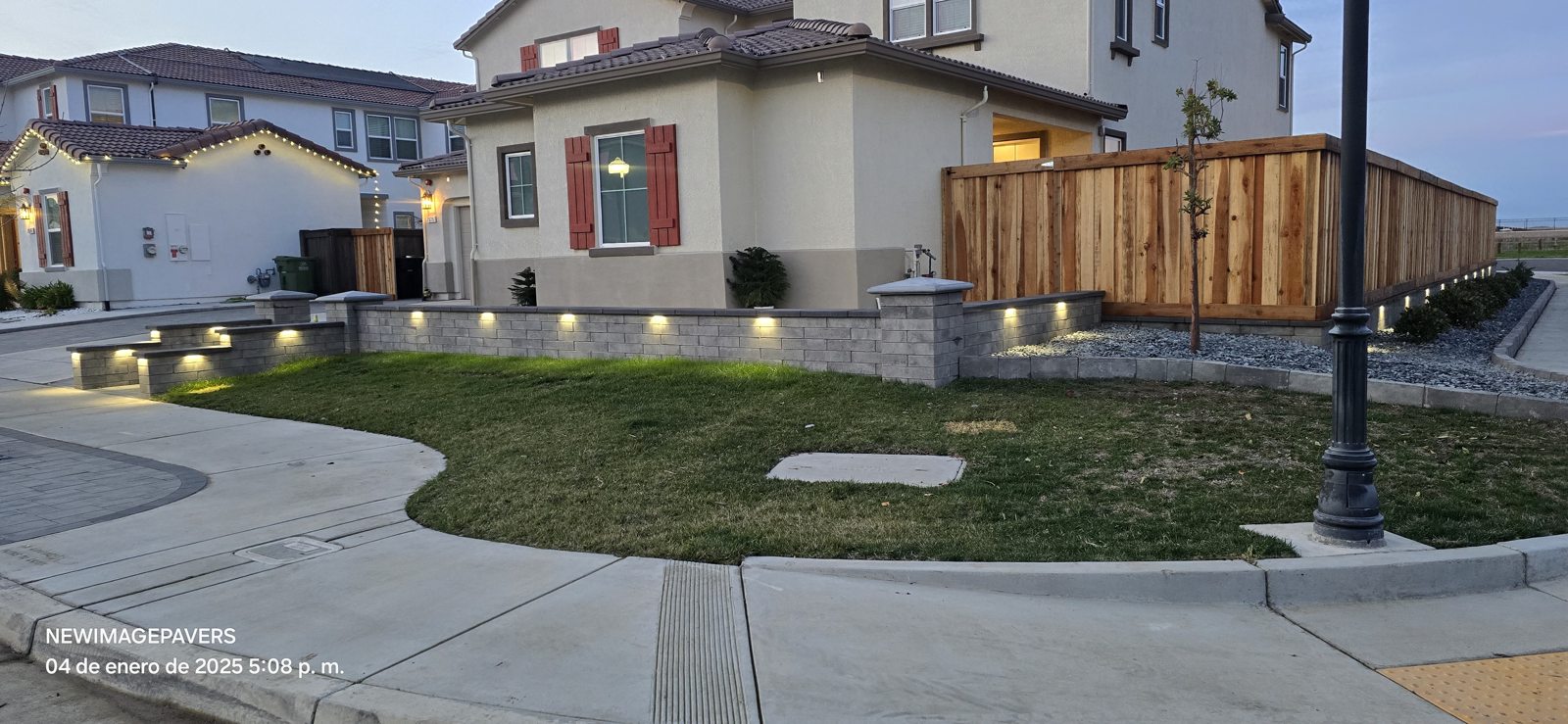 A curved lawn and illuminated wall give this corner entrance a refined finish.