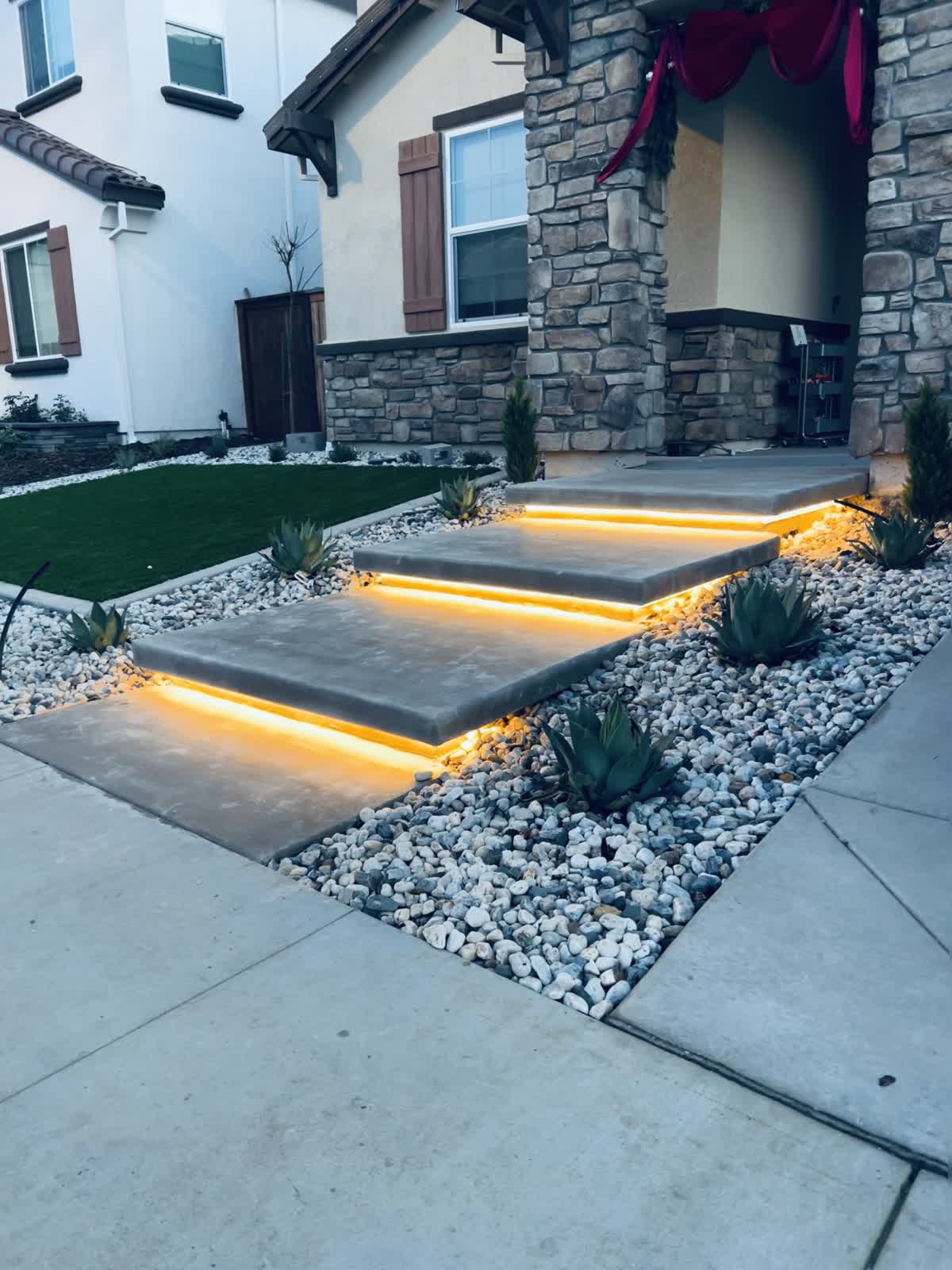 Warm step lighting gives the entrance definition against pale decorative stone.